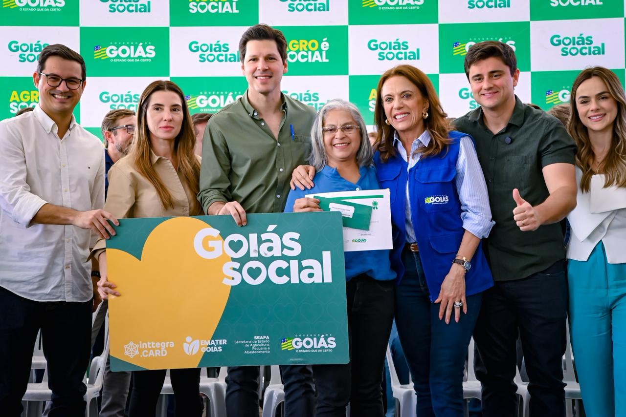 Daniel Vilela em cima de um palco, ao lado da esposa e de Gracinha Caiado, primeira-dama de Goiás, segu8rando um cartão do Goiás Social em evento.